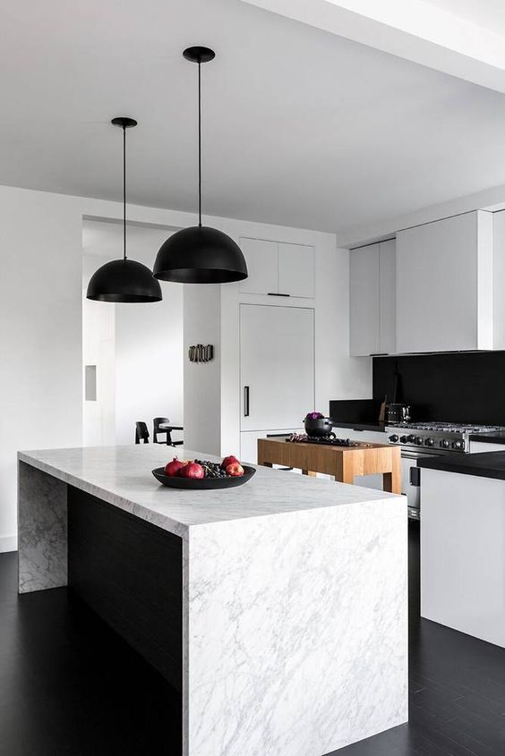 a contemporary black and white kitchen with sleek cabinets, black countertops and a backsplash, black pendant lamps