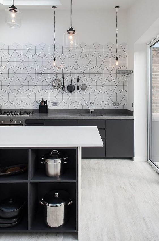 a contrasting Scandinavian kitchen in black, grey and white, black cabinets with grey countertops, a white kitchen island and hex tiles