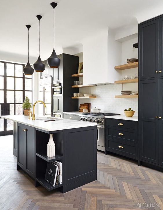 a lovely modern kitchen with black shaker cabinets and a kitchen island, white stone countertops, a white subway tile backsplash, black pendant lamps