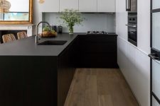 a minimalist kitchen with matte wihte and black cabinets, a large kitchen island, black built-in appliances and pendant lamps