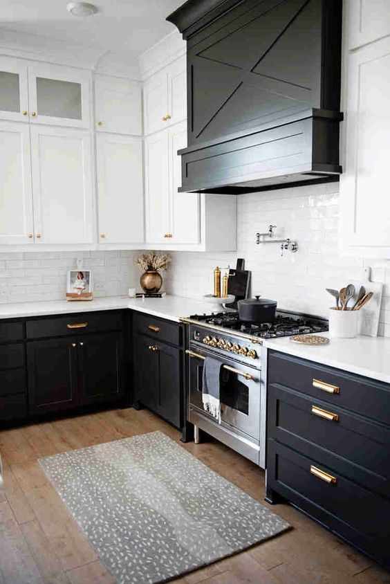 A Modern Farmhouse Kitchen With Black Lower Cabinets And White Upper Ones A Large Hood Covered With Wood And Gold Fixtures 