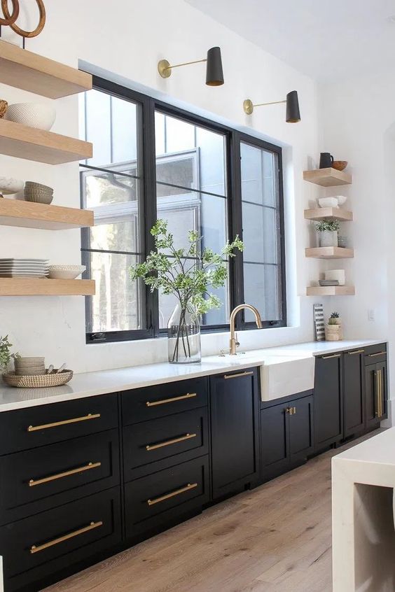 a modern farmhouse kitchen with black shaker cabinets, white countertops and statement flaoting shelves plus black and gold sconces