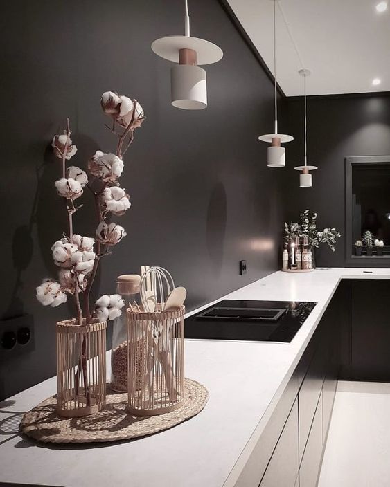 a moody black kitchen with black walls, glossy cabinets, white countertops and white pendant lamps is a stylish idea