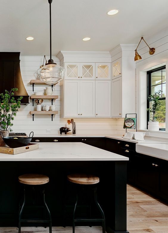 a refined farmhouse kitchen with white upper cabinets and black lower ones, white stone countertops and a white planked tile backsplash