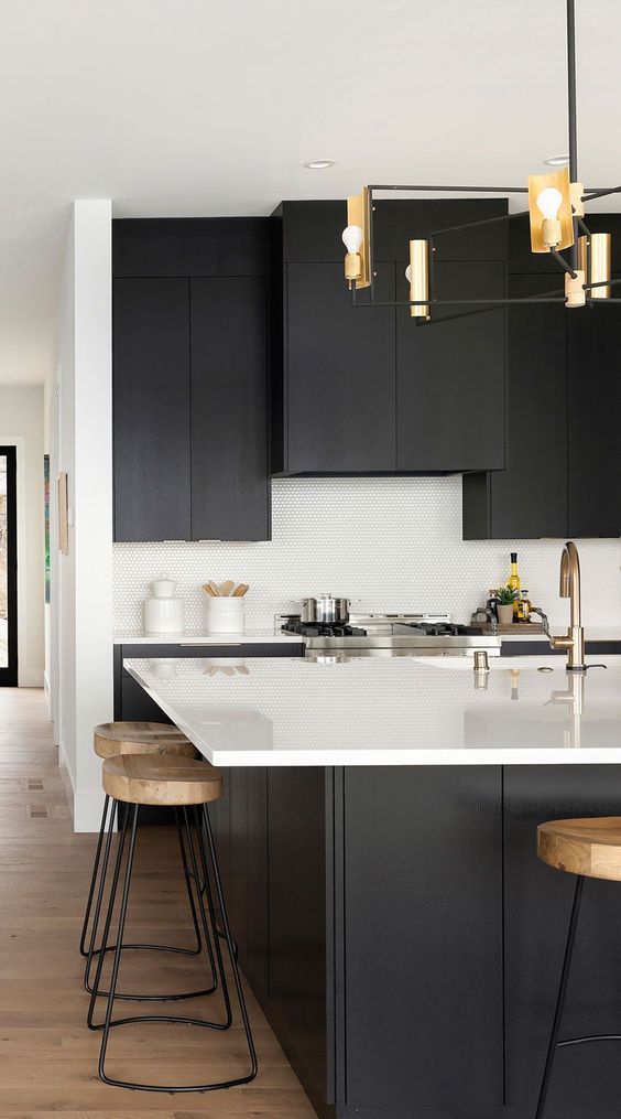 a sophisticated contemporary kitchen with matte black cabinets, white countertops, white penny tiles on the backsplash and an elegant chandelier