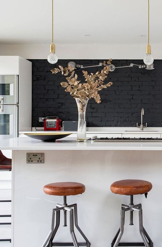 a stylish contemporary white kitchen with a black brick backsplash, pendant bulbs and touches of gold is chic and bold