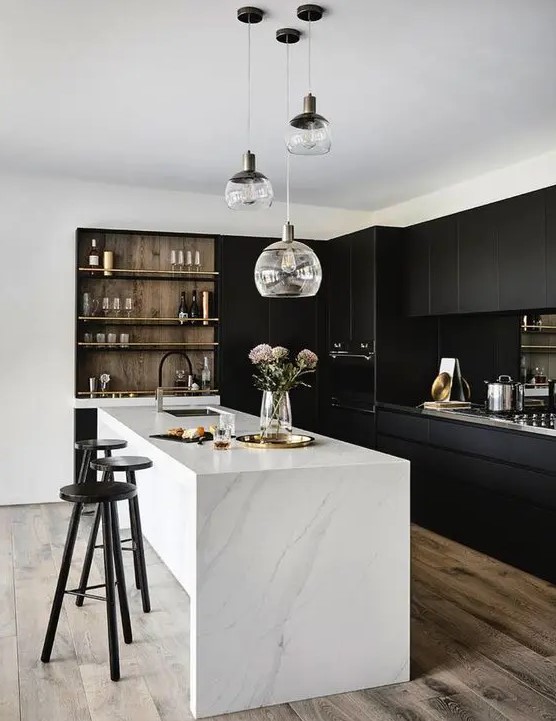 a stylish contrasting kitchen with sleek black cabinets, a white stone kitchen island, built-in shelves and a cluster of pendant lamps