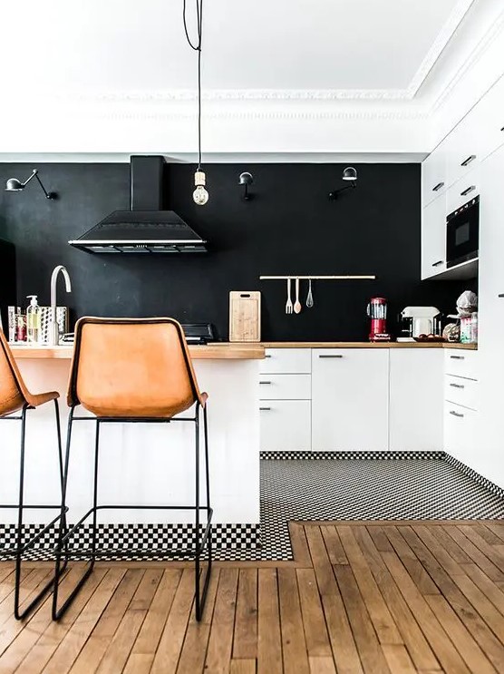 a stylish white kitchen with a large black chalkboard accent wall, butcherblock countertops, leather stools and a pendant lamp