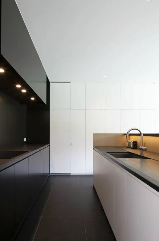 an ultra-minimalist black and white kitchen with sleek cabinets, concrete countertops, built-in lights and sleek surfaces