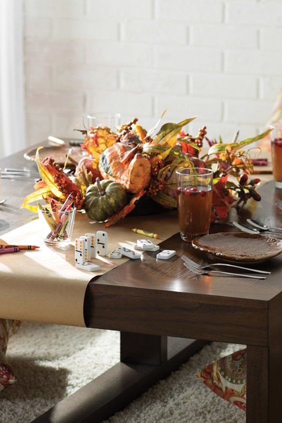 a bright Thanksgiving centerpiece of faux pumpkins, gourds, berries and leaves plus brown plates for a pretty table