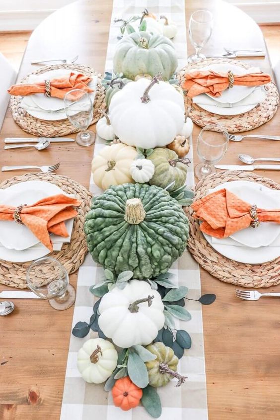 a bright and fun Thanksgiving table with leaves, pastel and whie pumpkins, woven chargers and orange napkins