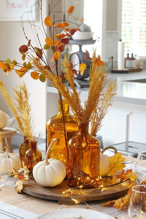 a gold and amber Thanksgiving arrangement with lights, leaves, wheat and pumpkins is a beautiful decoration