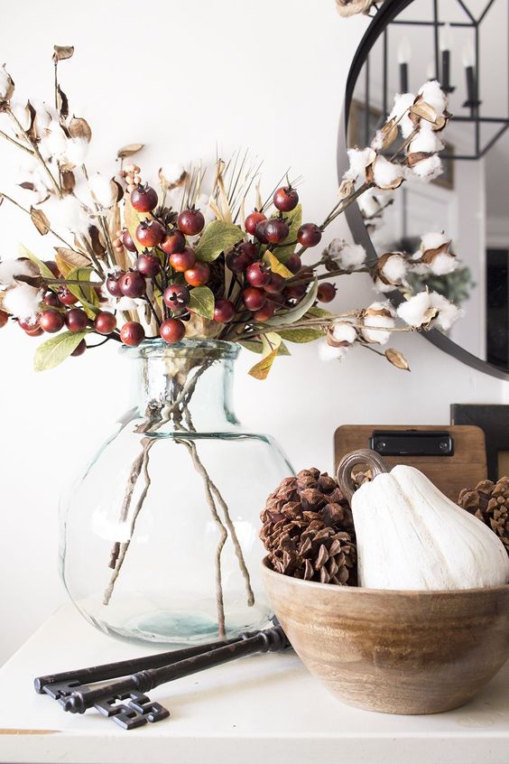 cozy fall decor with cotton branches, berries and greenery and a wooden bowl with a gourd and pinecones