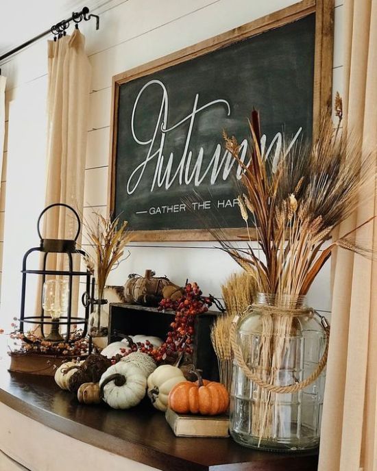 pretty fall or Thanksgiving decor with faux pumpkins, gourds, berries, wheat, a lantern and a large jar with wheat plus a chalkboard