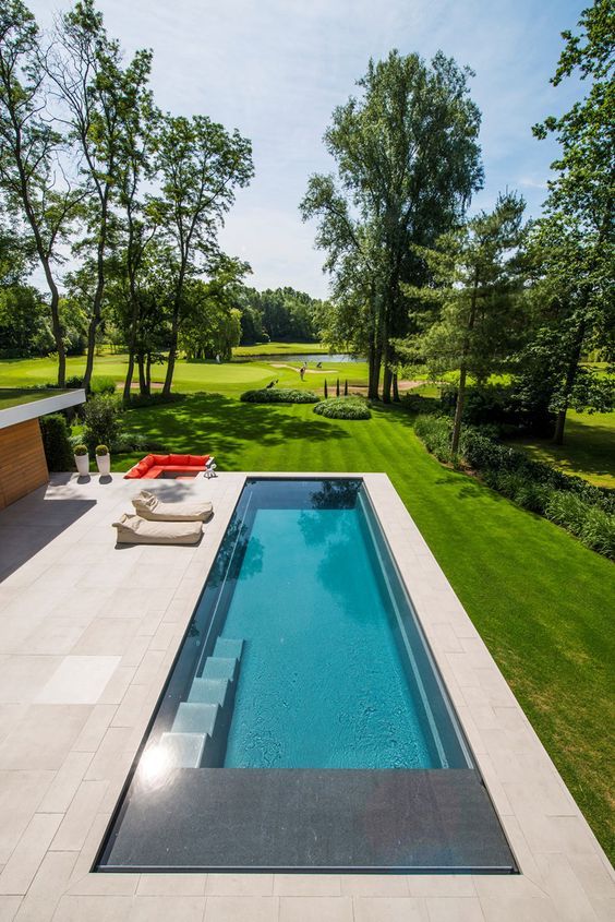 a contemporary outdoor space with an infinity pool, neutral stone tiles, soft loungers and a fire pit done in fiery red