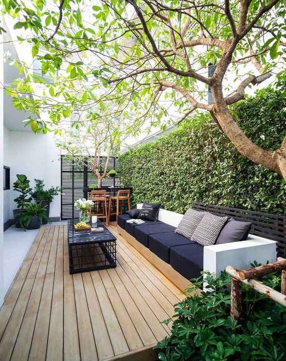 a contemporary outdoor living room with stylish furniture, a small bar and a living wall as a backdrop