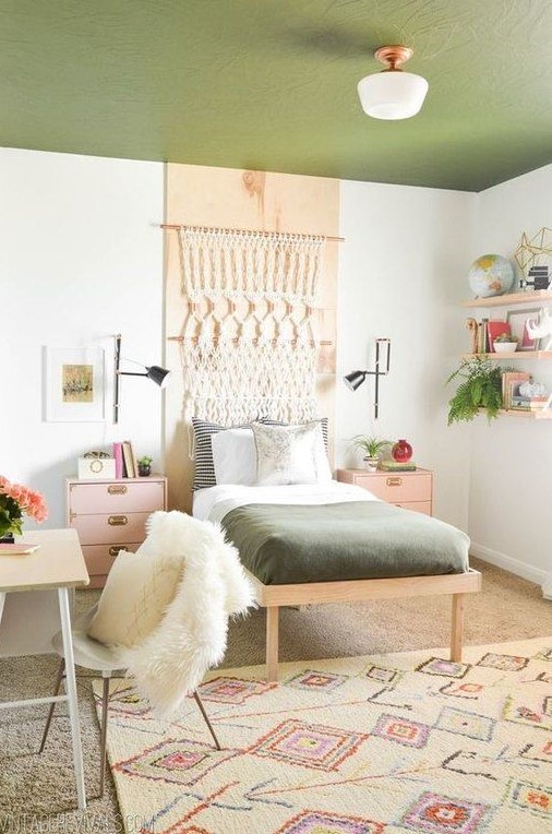 a boho teen room with a green ceiling, a macrame hanging, floating shelves, pink nightstands and a tiny desk and a chair