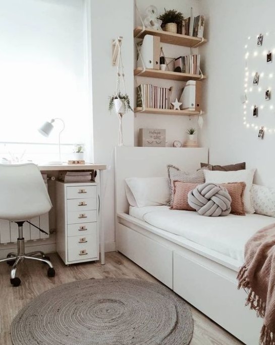 a chic neutral teen room with wall-mounted shelves, a comfy white bed with lots of pillows, a desk and a white chair plus potted plants