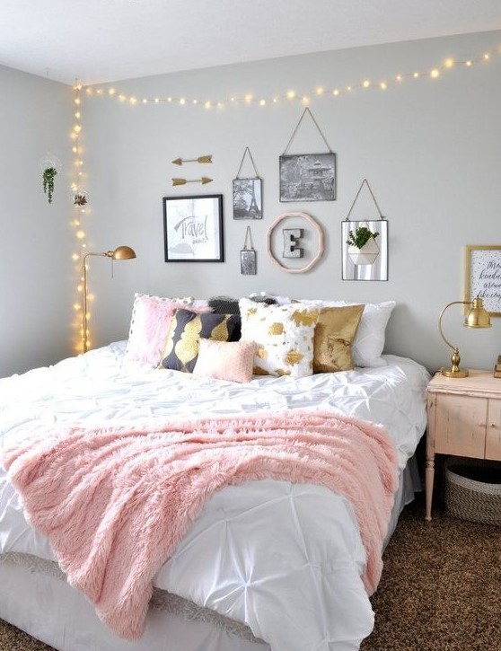 a chic teen girl bedroom with grey walls, a large bed with printed pillows, a lovely gallery wall and lights over the bed