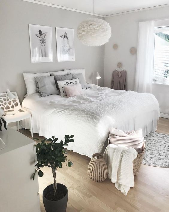 a cool neutral teen girl bedroom with a grey accent wall, a bed with neutral bedding, a white chair, a dresser, some artwork and a fluffy lamp
