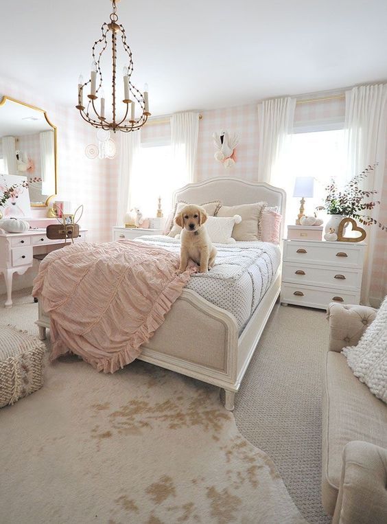 a neutral and lovely teen girl's bedroom with plaid wallpaper, a white bed with neutral bedding, white dressers, a blush vanity and a large mirror, a sofa