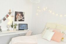 a neutral teen bedroom with a floating desk and vanity, a bed with pastel pillows and lights on the wall