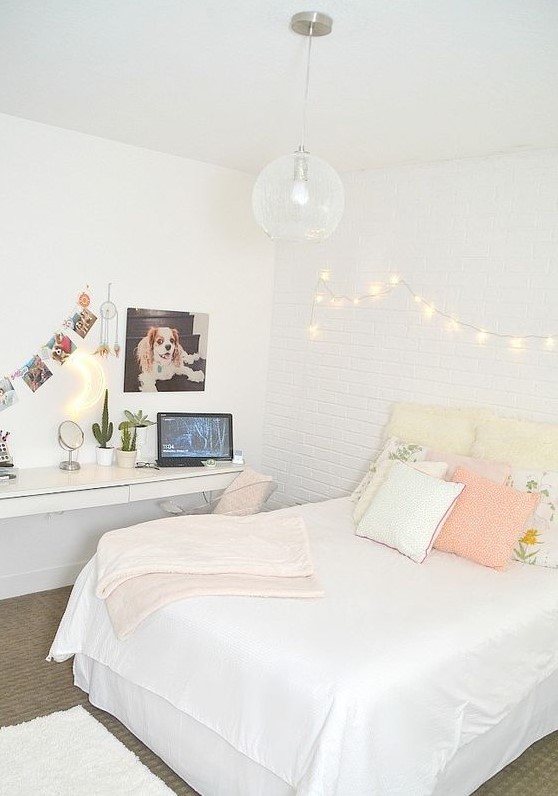 a neutral teen bedroom with a floating desk and vanity, a bed with pastel pillows and lights on the wall