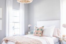 a pretty and relaxed teen girl bedroom with light grey walls, a white bed with pastel bedding, nightstands and tassel chandeliers