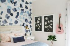 a pretty teen bedroom with a brushstroke accent wall, pink and blue textiles and a pink guitar on the wall