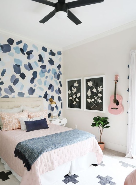 a pretty teen bedroom with a brushstroke accent wall, pink and blue textiles and a pink guitar on the wall