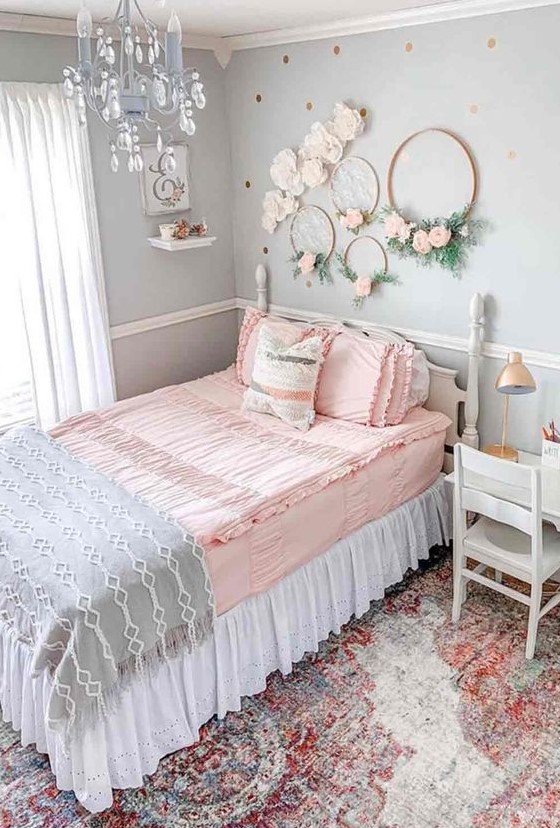 a romantic vintage teen bedroom with light blue walls, vintage neutral furniture, wreaths with blooms, a blue crystal chandelier and pastel bedding