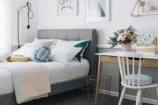 a stylish modern teen girl bedroom with a gallery wall, a grey upholstered bed, a small desk and touches of powder blue, blush and gold