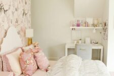 a teen girl bedroom in neutrals and pastels, with a floral accent wall, a white bed with printed and neutral bedding, a blush nightstand, a white desk and a grey chair