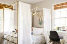a welcoming modern teen girl bedroom with a brass canopy bed with lights, some boho decor and various textiles for styling the room