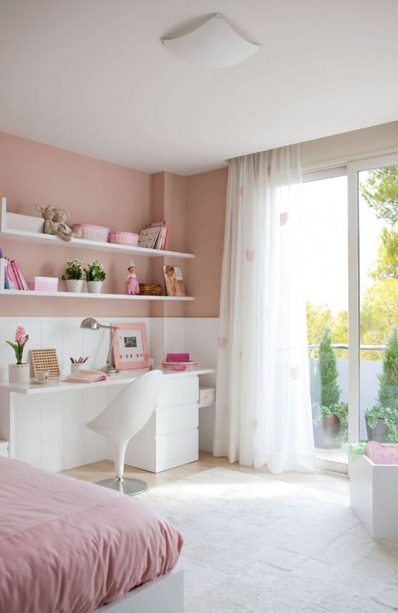 a contemporary pink teen bedroom with a white desk, heart print curtains, open shelves and a bed with pink bedding