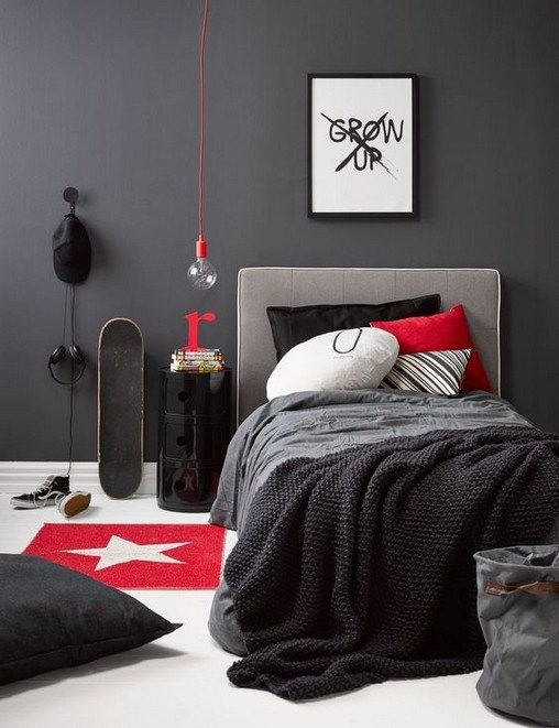a dark contemproary teen bedroom with an upholstered bed, a hanging bulb, bold pillows and an artwork