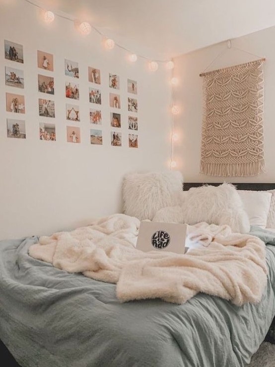 a boho teen bedroom with a black bed with white and blue bedding, a macrame hanging, lights and a grid gallery wall