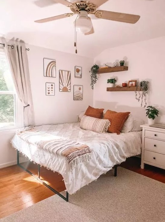 a boho teen bedroom with a metal bed, a gallery wall, wall-mounted shelves, a white dresser, potted greenery and neutral textiles