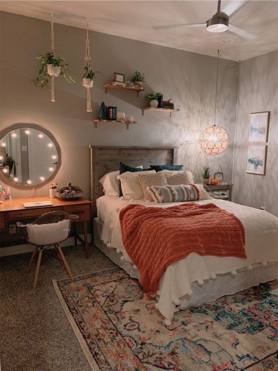 a boho teen bedroom with grey walls, a bed with a reclaimed headboard, a vanity as a makeup table, a bright rug and potted plants