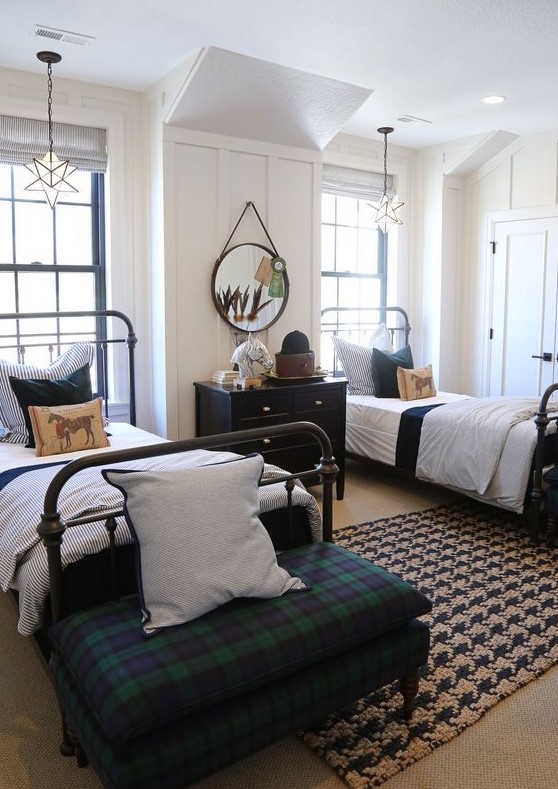 a bold shared boy bedroom with metal beds, a black sideboard, a plaid ottoman and cool star lamps