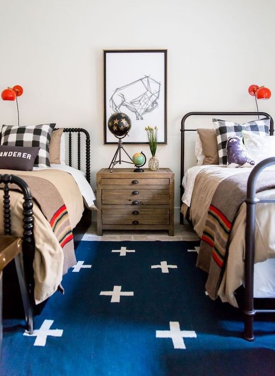 a bold shared teen boy bedroom with black beds, layered rugs, bright bedding, a gallery wall and red sconces