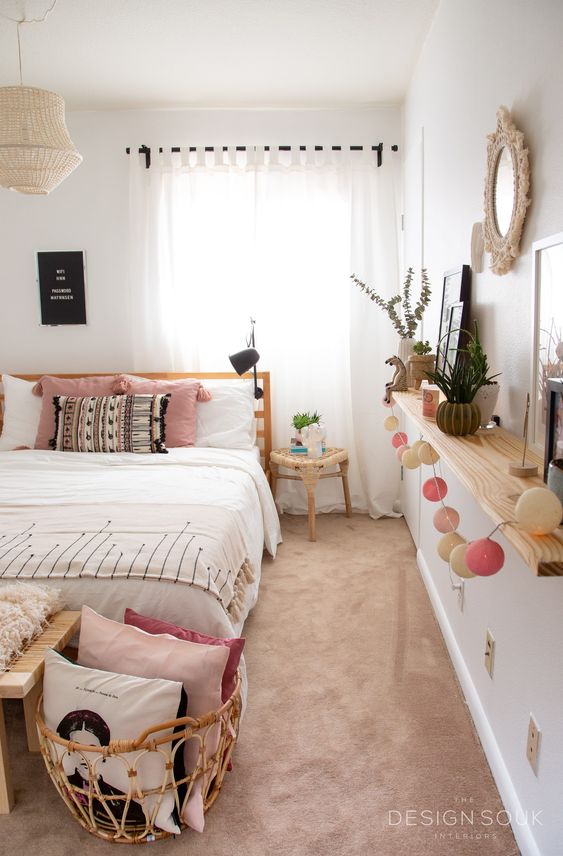 a cool boho teen bedroom with an open shelf that features decor and greenery, a wooden bed, a bench and a rattan basket