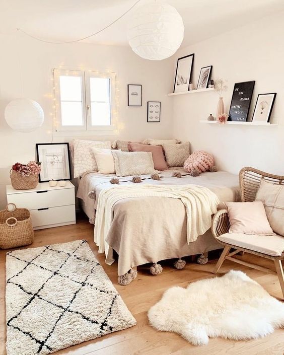 a cozy Scandinavian teen bedroom with a bed with neutral and pastel bedding, a nightstand, a rattan chair, a ledge gallery wall and pastel pillows