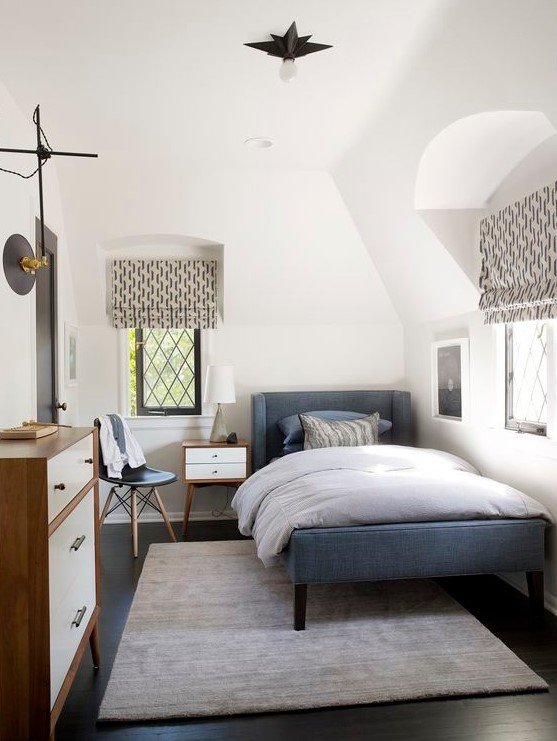 a cozy mid-century modern teen room with a blue upholstered bed, a dresser, printed textiles, a small nightstand and a chair