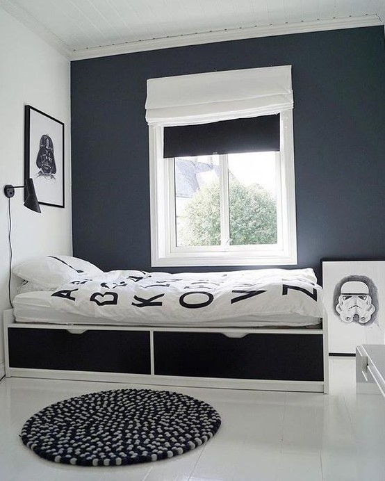 a laconic contrasting teen bedroom with black and white walls, a bed with drawers, black and white shades and artworks
