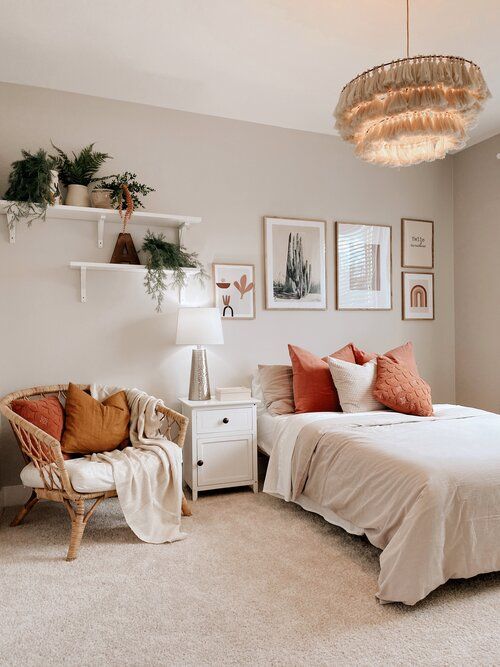 a lovely boho bedroom with grey walls, a bed with neutral bedding, a rattan chair with pillows, shelves with greenery