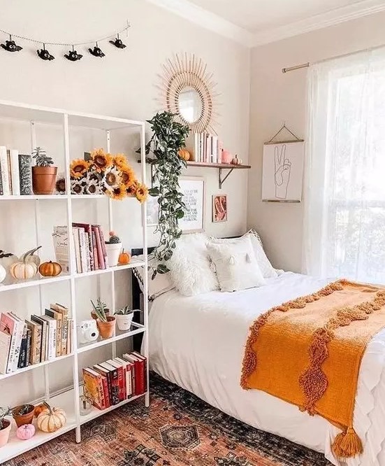 a lovely teen room with a black bed, a large open storage shelf with blooms and pumpkins, a shelf and a mirror over the bed