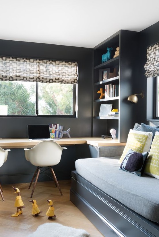 a moody teen bedroom with a bed, a built-in desk and a storage unit, a couple of chairs and printed textiles