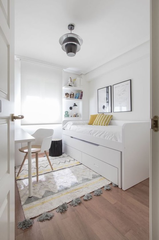 a neutral Scandinavian bedroom with a bed with storage, a desk and a chair, built-in shelves and a printed rug