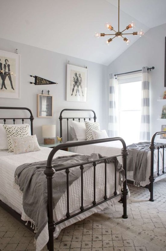 a neutral attic shared boy bedroom with metal beds, a gallery wall and a chandelier is a chic space